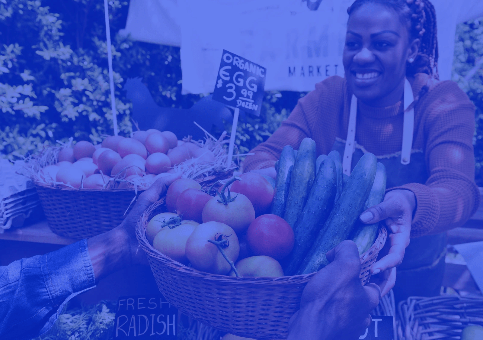 A farmers market vendor handing over a basket of fresh produce